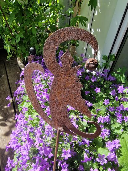 Eine Figur aus Eisen mit Rost auf einem Stab. Mein Zaubererkönig vor blauen Glockenblumen