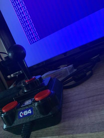 A picture of C64 DTV toy game console connected to LCD TV. TV displays output of following BASIC program running on C64 BASIC:

10 PRINT "UWU"
20 GOTO 10
