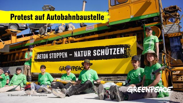 Greenpeace-Aktive protestieren an einer Autobahnbaustelle mit einem Banner. Auf diesem steht: Beton stoppen - Natur schützen