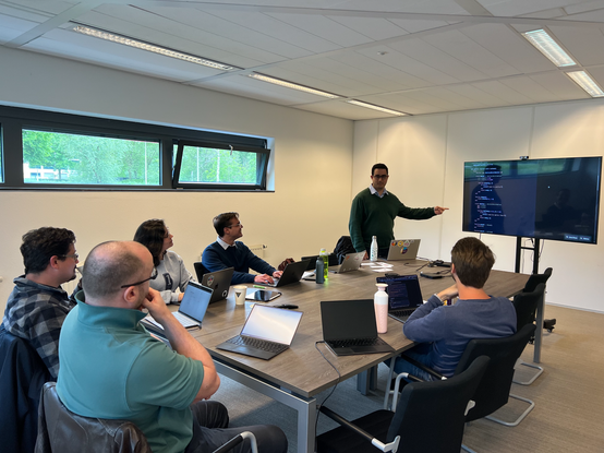 Our colleagues sitting around the table, Abel Siqueiras is explaining JuliaLang on a presentation screen.