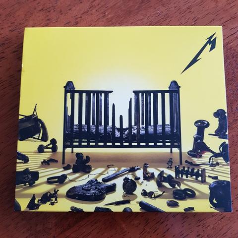 Cover of new Metallica album 72 Seasons, featuring a charred cot and various blackened images lying on the floor.