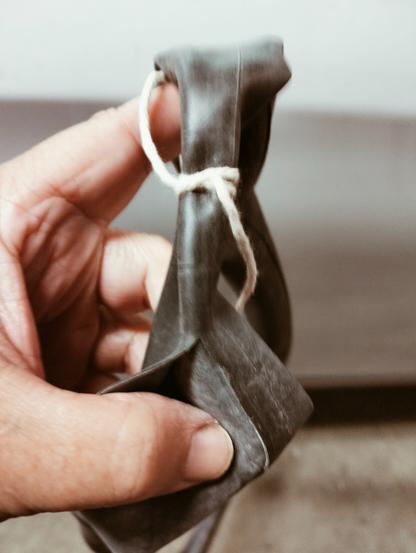 A constrictor knot tied around a bicycle inner tube, above a long slash in the tube.