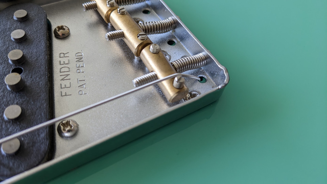 Low e string on the vintage style brass saddle of a Fender Vintera Telecaster guitar.