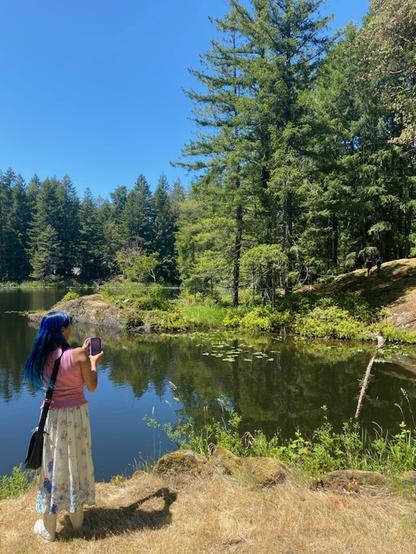 Photo of my backside, taking photo of my friends up on cliffside trail, from across lake waters. Photo from new friend, Monica.