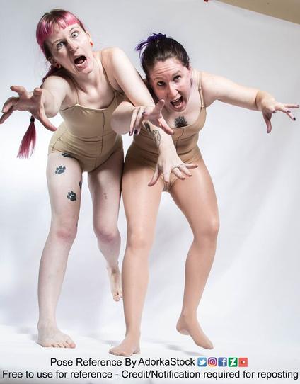 Two people are standing with both of their arms sticking out in such a way to seem like they might be zombies!