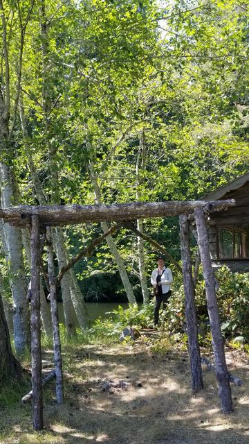 Open archway entrance to a cabin, made from fallen tree branches.