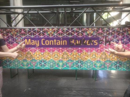 Ein "May Contain Hackers"-Banner, bei dem das "Hackers" überklebt wurde, so dass dort nun "May Contain Gulasch" steht.