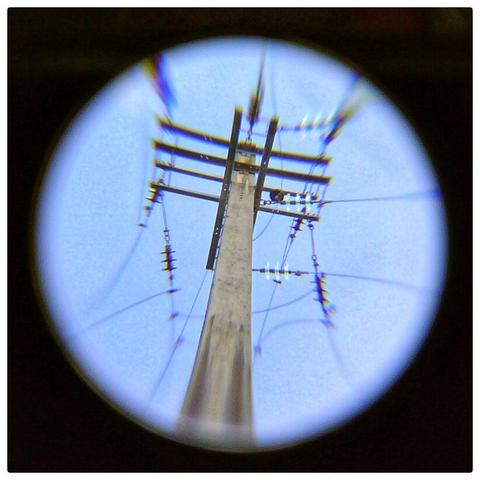 The top of an electricity pole against a blue sky. Wires go out of the frame in all directions. A knocked about Panavision super wide AF macro 0.42x wide angle adapter was held over the PSP camera lens, but reversed.