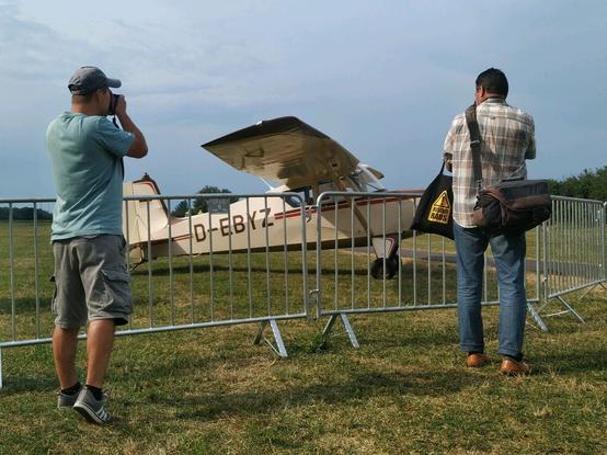Two pro photographers taking pictures of aircraft on display behind fence.
