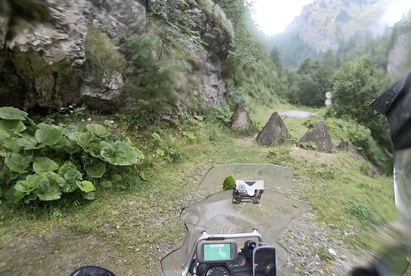 Vista des d'una càmera de casc, un camí de muntanya en un congost tallat per uns pilons de formigó, asfaltat a l'altre costat