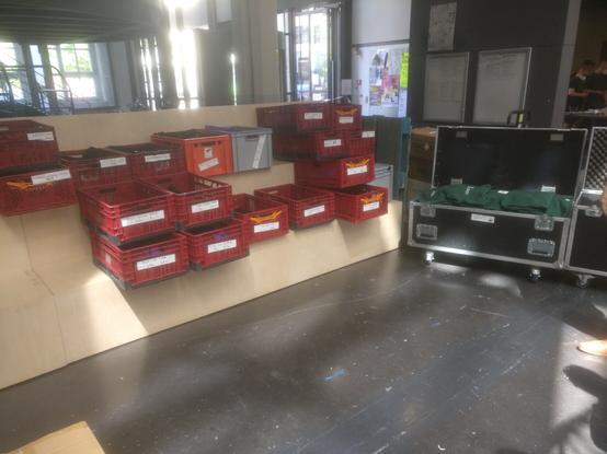 Sehr viele Eurokisten und Flightcases voller Merch stehen auf einer Holztribüne