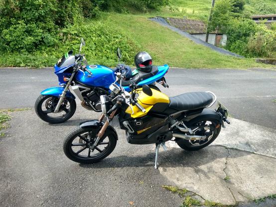 Blue 2007 Kawasaki Balius II and yellow 2021 SuperSoco motorcycles in driveway