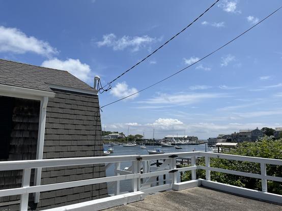 Photo shows an ocean inlet with many boats, blue water and blue sky in the background