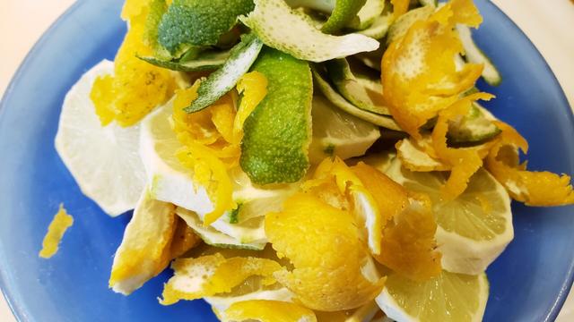 Sliced Lemons and limes and their peelings on a plate.