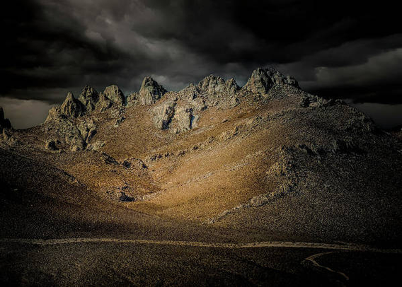 The Eastern Sierra mountains in California, near Lone PIne in a storm, highlights still on the mountain. here:

https://pixels.com/featured/eastern-sierra-evening-storms-norma-brandsberg.html