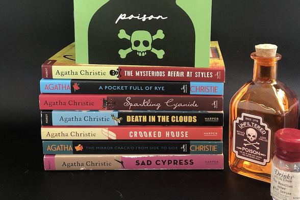Pile of 8 A. Christie books, with two bottles of poison on the right.