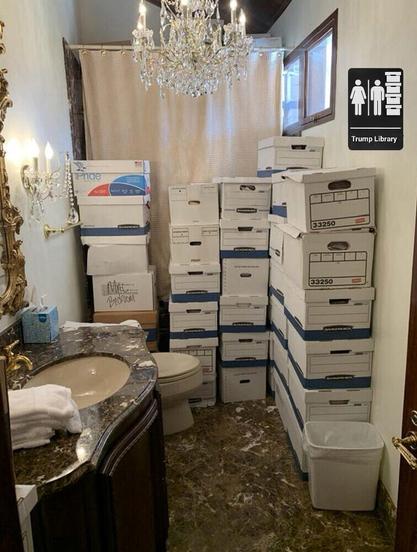 Bathroom with chandelier,  secret documents and tension shower curtain rod.

Has restroom sign that says Trump library and has file boxes