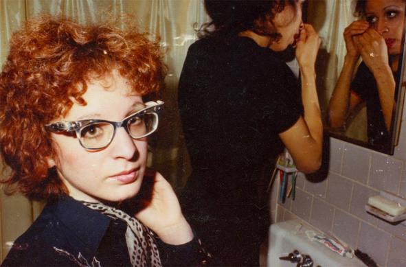 Eine rothaarige Frau schaut in die Kamera, neben ihr schminkt sich eine Frau vor einem Spiegel: Nan Goldin in ALL THE BEAUTY AND THE BLOODSHED © PLAION Pictures