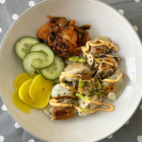 Lunch plate with dumplings, cucumber, pickled radish and kimchi