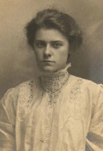 Katherine G. Ecob, from the 1909 yearbook of Bryn Mawr College; a young white woman with hair in a bouffant style, wearing a lacy white blouse with a high collar