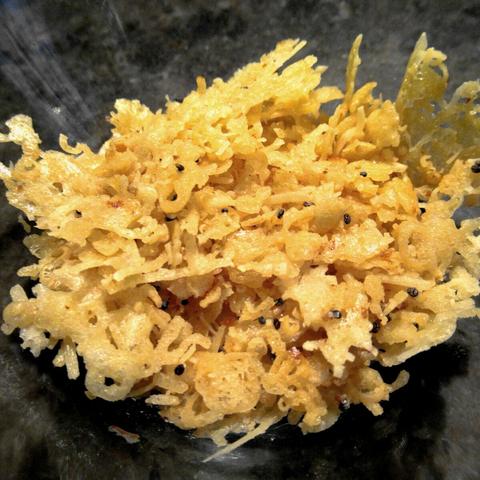 Flocken der Reste von einer Käsekruste nach dem Backen.
