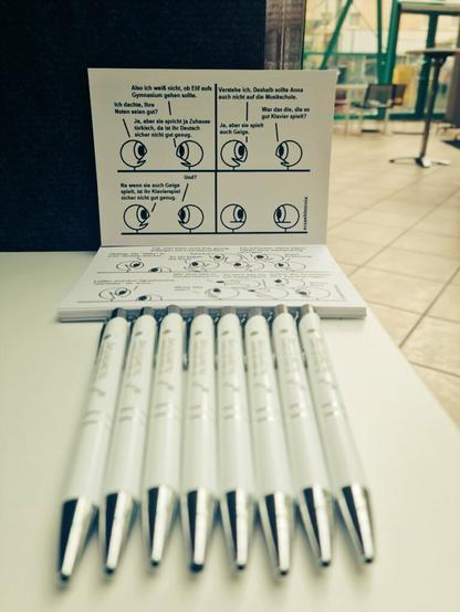 Comic-Postkarten und Kugelschreiber liegen zum Mitnehmen aus.