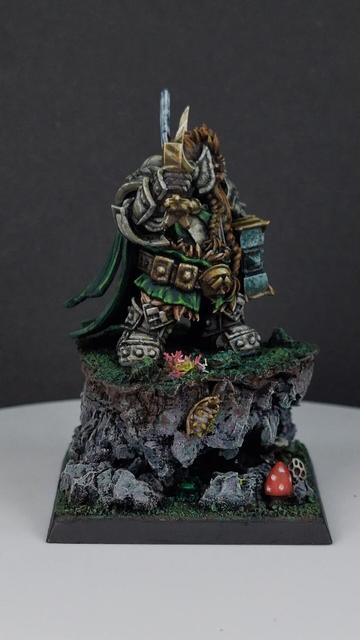Dwarf paladin miniature standing on grassy outcrop with a small cave underneath wearing stone armour, carrying a sword and hammer with tiny insects and animals around