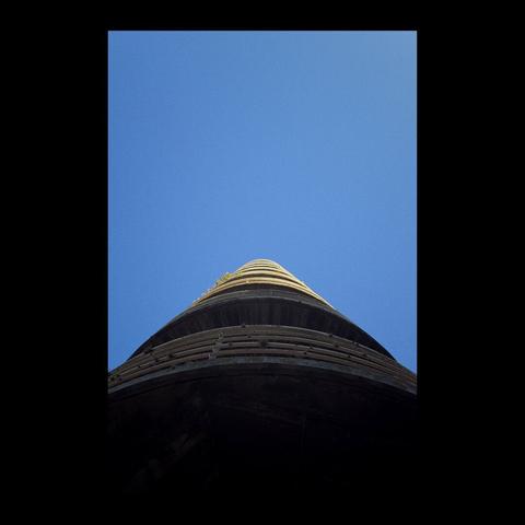 # Español

La mayoría de la fotografía se ve dominada por un cielo intensamente azul que reina desde arriba. Erigiéndose cuál una pirámide desde la parte inferior de la imagen, se puede ver una superposición de balcones circulares desde abajo, uno apilado uno arriba del otro, fugándose hacia el centro de la imagen.

# English

Most of the photograph is dominated by an intensely blue sky. Rising like a pyramid from the bottom of the picture, a superposition of circular balconies can be seen from below, one above the other, vanishing towards the centre of the image.