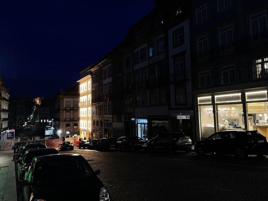 Fachadas de edifício comercial de 4 andares no Porto, à noite, com 28 janelas, cada uma circundada por 32 lâmpadas LED ligadas. O edifício destaca-se dos restantes pelo intenso brilho e poluição luminosa.