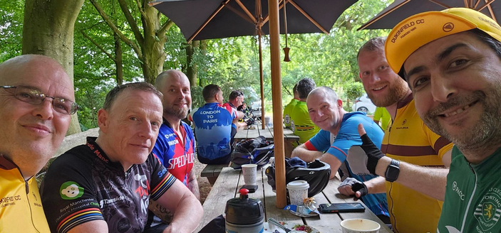 Six male cyclists pose for a group selfie