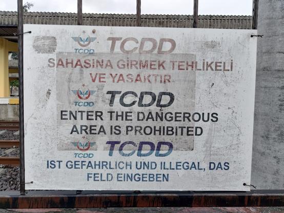 Hinweistafel auf Türkisch, Englisch und Deutsch. Auf deutsch steht der Text "Ist gefährlich und illegal, das Feld eingeben."
