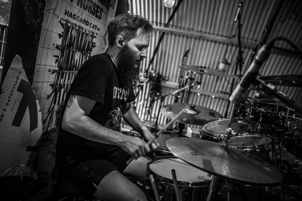 Black and white photograph of me, playing the drums in a live setting, sweating because of the heat and intensity.
