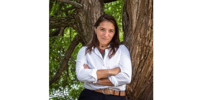 Portrait of Chloe Fouilloux with her arms crossed leaning against a tree