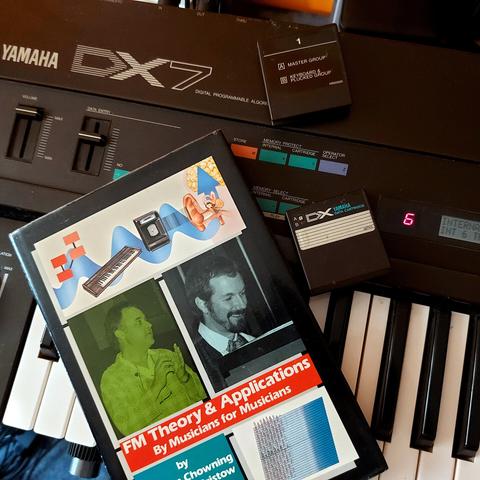 Photo of my Yamaha DX7 with sound cartridges and a book guide that is also rare ot find now.
