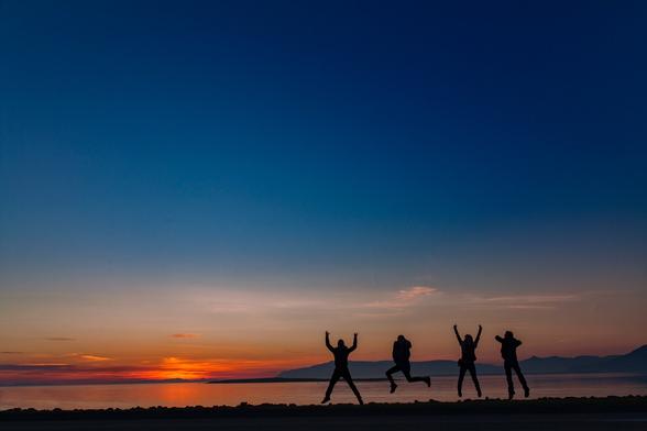 Midnight sun in Iceland. Taken in Reykjavik by the shore of the ocean overlooking the sun set at midnight, with four people in the foreground jumping with glee.