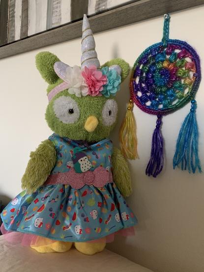 Wendy radiates sheer summer elegance as she adorns her brand new Hello Kitty summer dress. The dress, an enchanting symphony of blues, showcases a captivating tapestry of delightful summer motifs. Watermelons, popsicles, sunglasses, parrots, toucans, flowers, and an abundance of other joyful elements dance across its fabric. Enhancing its allure, a resplendent sparkly pink belt adorned with a dainty bow graces the waistline, while a cascading pink ruffle adds a touch of whimsy to the hem. Completing her ensemble with finesse, Wendy wears a charming floral accessory accompanied by a unicorn horn, accentuating her unique style.

Captivating our attention nearby is a mesmerizing wall hanging, meticulously handcrafted with vibrant yarn. Wendy eagerly showcases this masterpiece—a radiant dream-catcher bursting with a kaleidoscope of rainbow hues. Delicate strands intertwine, forming an intricate web that captures dreams and aspirations. Three meticulously beaded tassels gently sway, reflecting light and enchanting all who lay their gaze upon it. Its irresistible beauty is undeniable, a testament to the skill and artistry poured into its creation.