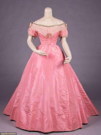 2-pc gown of pink silk taffeta, puff sleeves overlaid w/ net, pleated net across front, over SHs & to CB, trio of cloth roses to SHs & CF, black silk velvet ribbon inserted to lace at bateau neckline & sleeve cuffs, CB closure w/ silk eyelet, gored & trained skirt w/ cartridge pleated