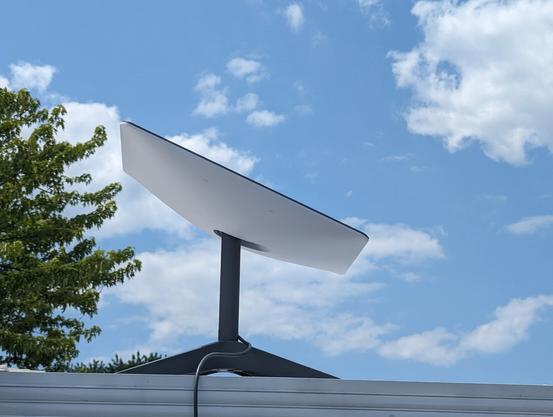 A Starlink Dishy on a roof in front of a blue sky