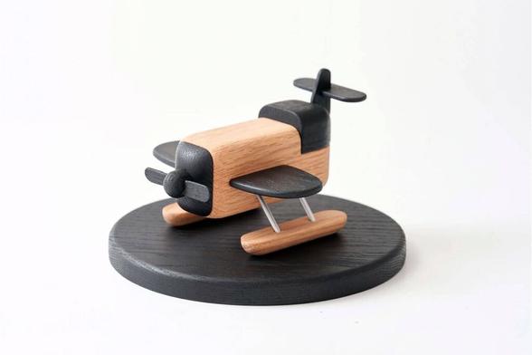 A minimalist toy aeroplane made out of wood by Korean studio S2 VICTOR in natural and dark wood tones, with soft rounded edges.