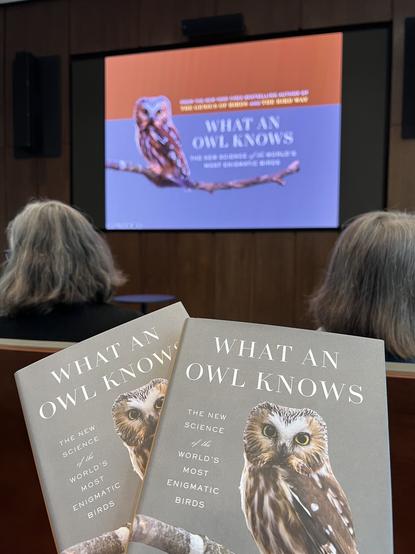 Photo of book covers titled "What an Owl Knows" by Jennifer Ackerman. Screen in background is firs slide of author's presentation.