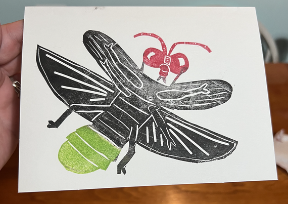 a lightning bug linocut with a red head black body and green butt
