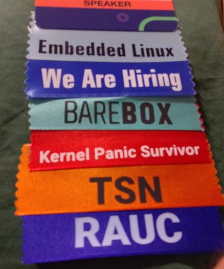 Ribbons an einer Conference -Badge: Embedded Linux, We Are Hiring, Barebox, Kernel Panic Survivor, TSN, RAUC