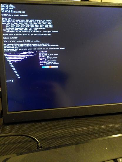 Photo of a portable monitor attached via HDMI to a Rock5B, showing neofetch output indicating NetBSD