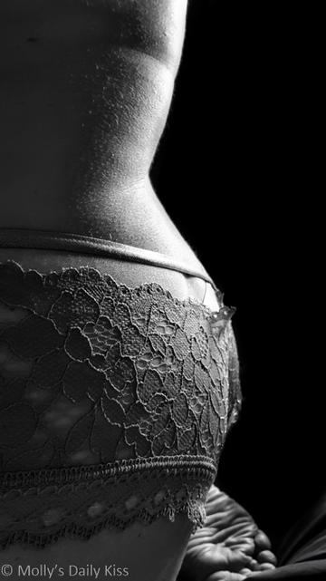 Black and White Side view of molly kneeling wearing lace knickers with ribbon ties across the top of her buttocks