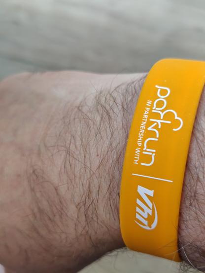 Hairy wrist with a yellow rubber wristband with Parkrun printed on it