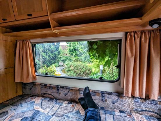 Blick aus einem Wohnwagen in einen grünen Garten.