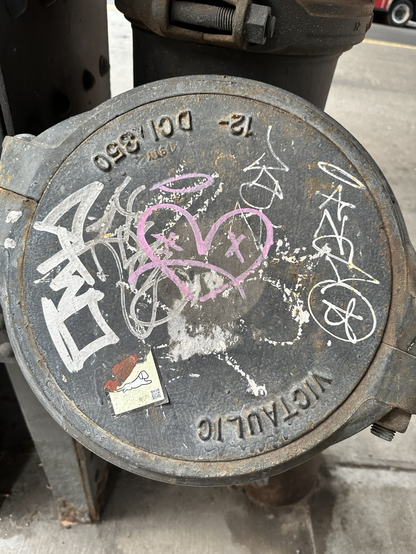 various tags on a round steel plate including ANSO on the right and a pink heart in the middle