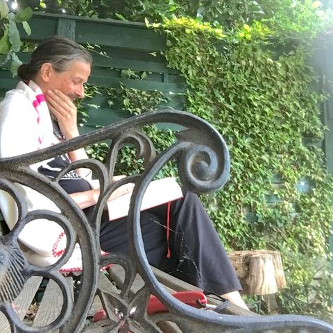 Molo mit Decki auf Gartenbank umgeben von Grün schmunzelt beim Lesen von »Heike Monogatari« (Reclam Verlag 2022).