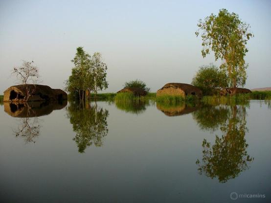Llac Débo, que es forma en mig del riu Níger, a on es reflexen perfectament les cabanes i els arbres que hi ha a terra ferma.