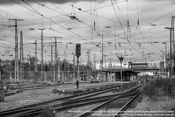 Blick von Norden auf die Bahnsteige des unteren Bahnhofsteils von Falkenberg (Elster) am 17.01.2023. Die Hektometertafel "148,0" gehört zur Strecke 6207, Węgliniec -- Roßlau (Elbe). Die Bahnsteigmitte liegt in km 147,9 dieser Strecke sowie in km 112,2 der Strecke  6133 (Jüterbog -- Zeithain Bogendreieck). Rechts befindet sich der Hausbahnsteig mit dem Gleis 1M (Kundengleis 1), daneben der Inselbahnsteig mit den Gleisen 2M und 5M (Kundengleise 2 und 3). Das Gleis 4M (für den Reiseverkehr nicht genutzt und daher bei der Kundengleis-Nummerierung unberücksichtigt) endet stumpf am Inselbahnsteig, was an der Sh-2-Tafel im Bild gut erkennbar ist. Ganz links folgt schließlich der Seitenbahnsteig mit dem Gleis 6M (Kundengleis 4). Links davon führt das Gleis 59 zum oberen Bahnhofsteil Richtung Osten (zum oberen Gbf). Auf die Strecke 6207 in Richtung Wahrenbrück -- Bad Liebenwerda kann nur über die linken Gleise 5M und 6M ausgefahren werden. Die Signale gehören sämtlich zum Hl-System. Schwarz/weiß-Bearbeitung des Bildes.
